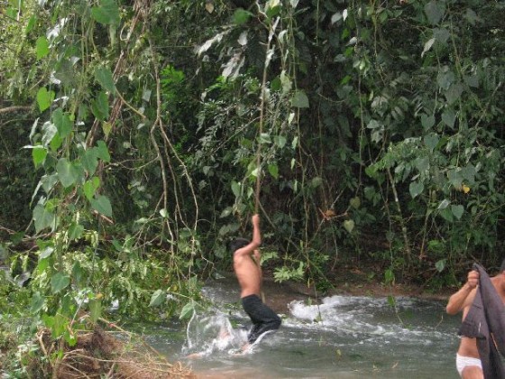 Junge schwingt an einer Liane über den Fluss