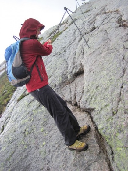 Martina lässt sich an einer Kette den steilen, rutschigen Fels runter